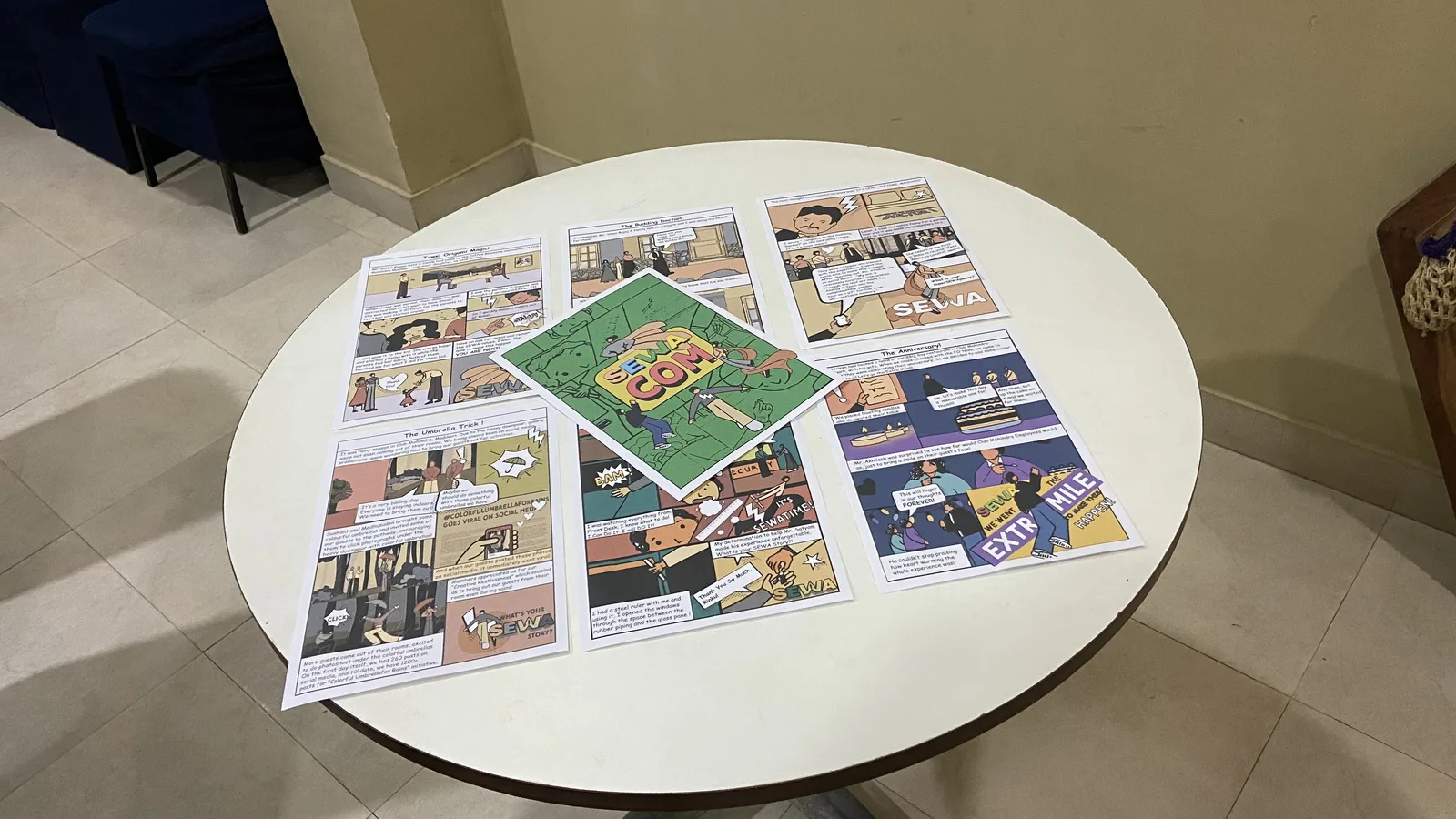 Printed SEWA Comics booklet and comic pages from the Coorg project, laid out on a white table.